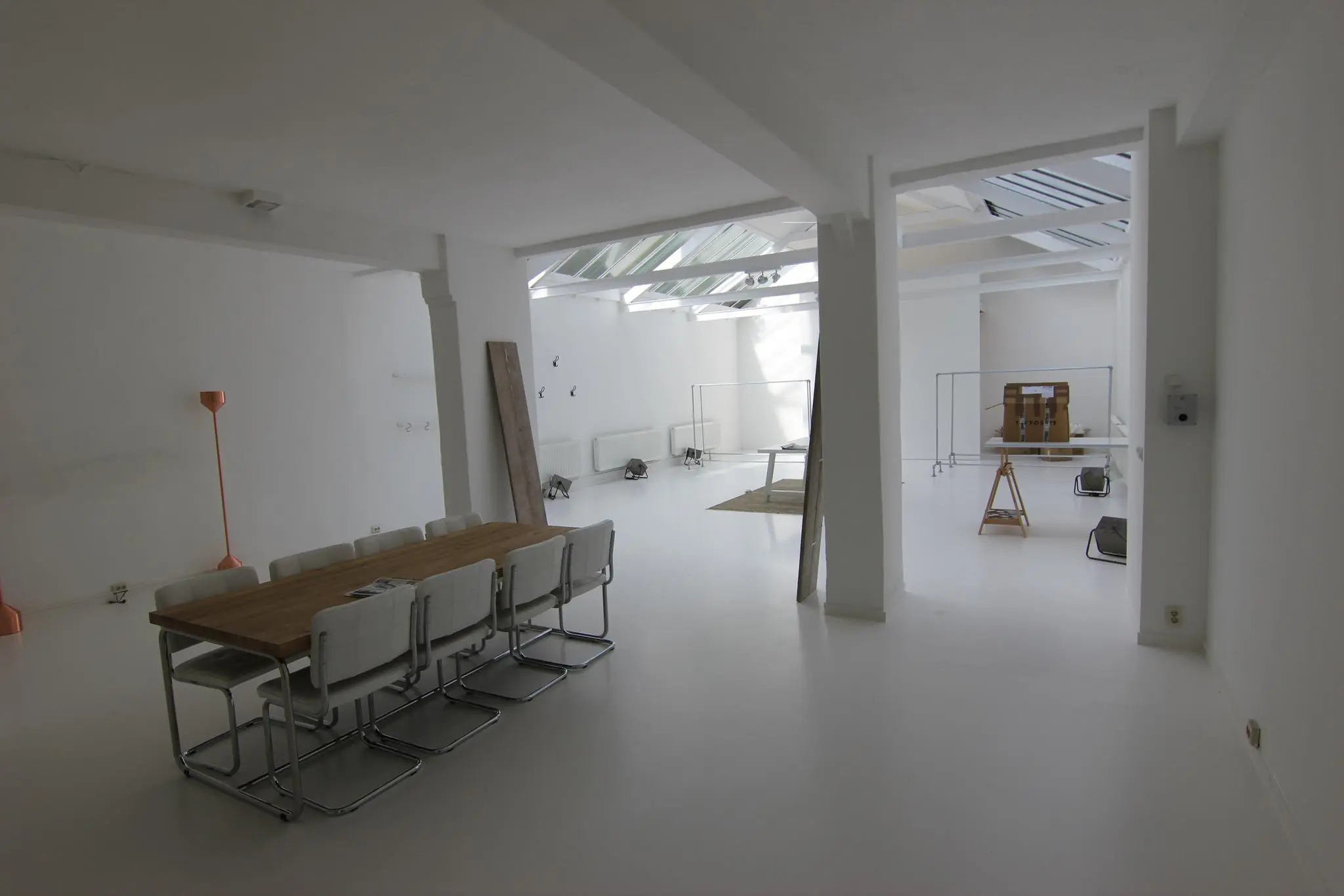 Licht en minimalistisch ingericht interieur in een ruimte aan de Graaf Florisstraat met een houten tafel, witte stoelen en een glazen dak.